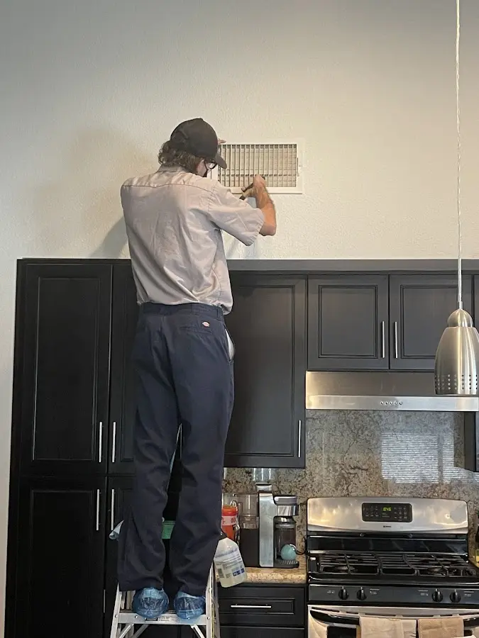 Technician inspecting an air vent during HVAC service in Burlington